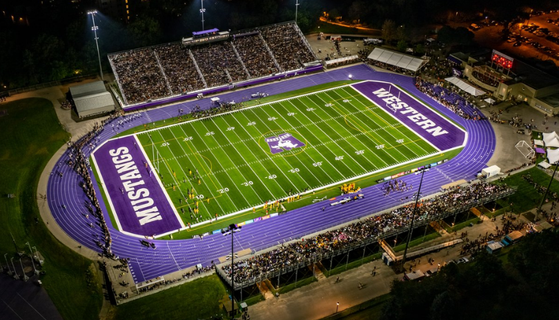 Western Alumni Stadium lit up for a football game at night.